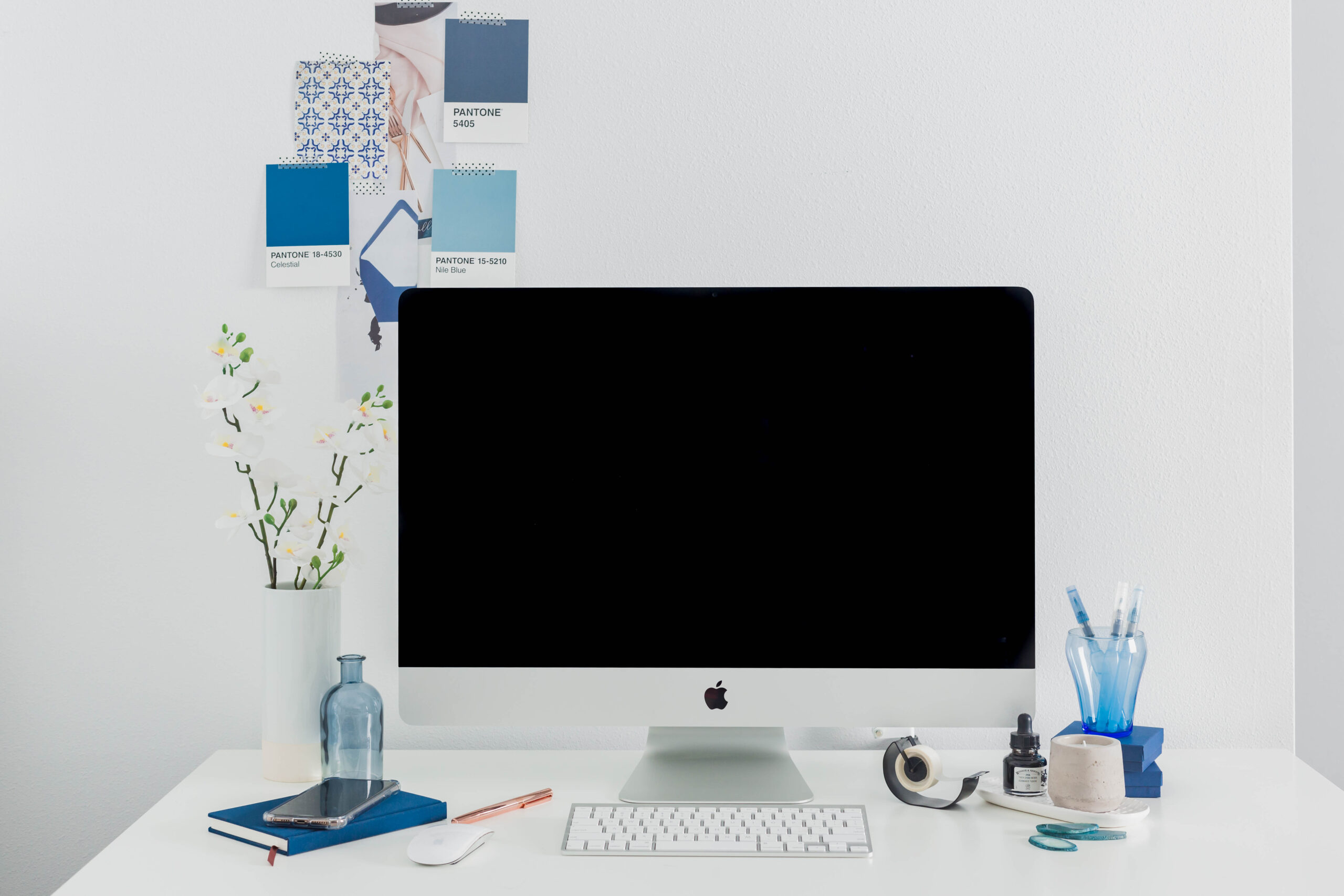 Imac sitting on a white desk with blue accent decorations