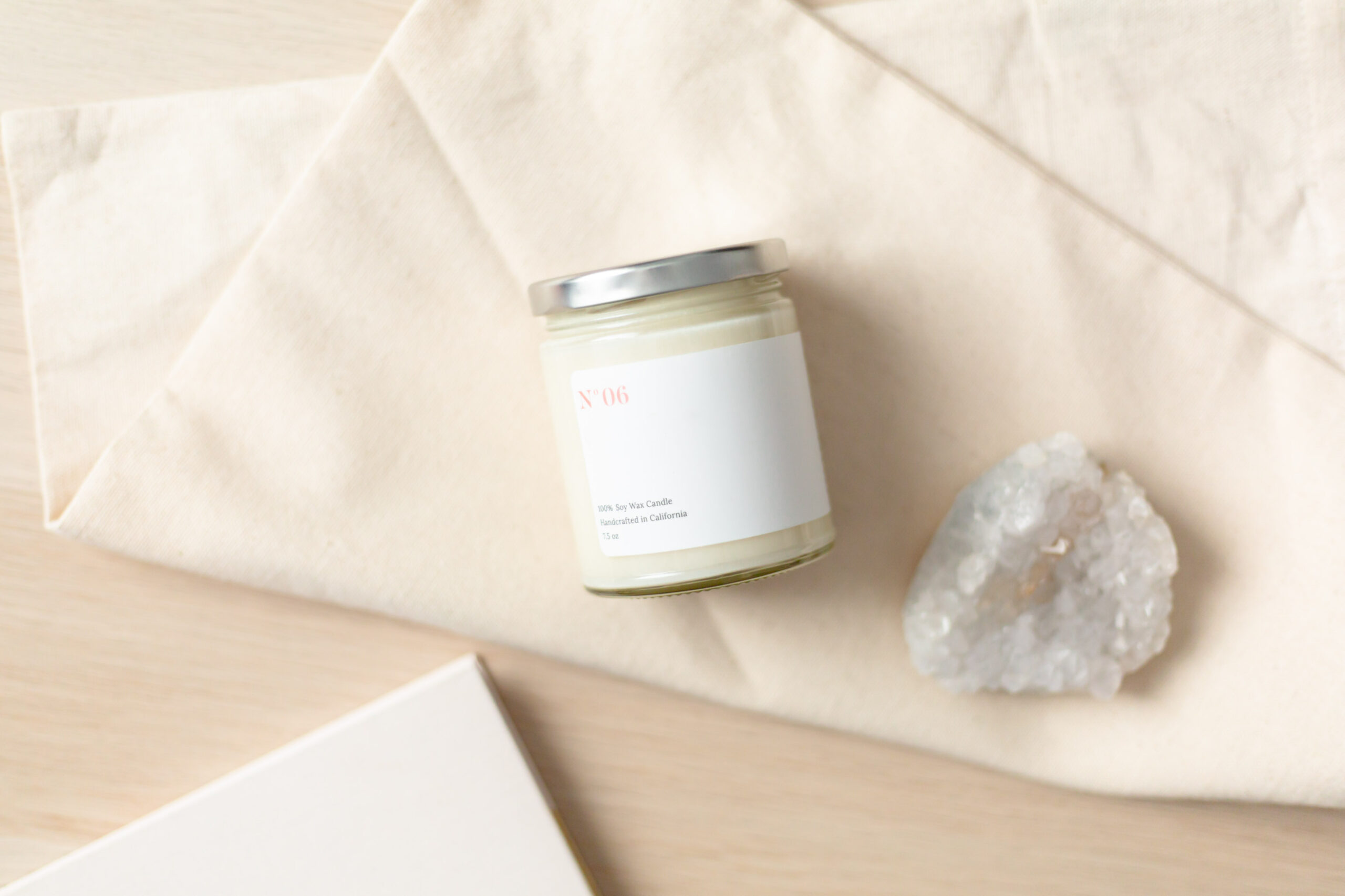 Candle on a table with a clear quartz next to it